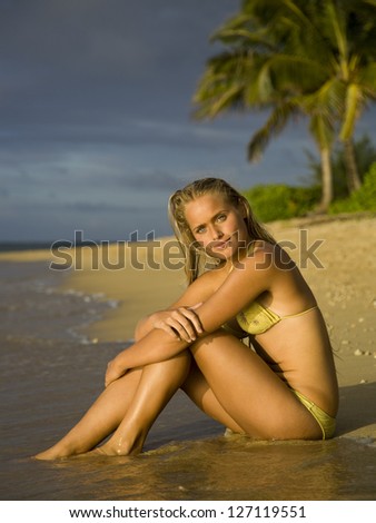 Teenage girl sitting on the beach and hugging her knees