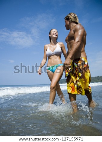 Low angle view of a young couple wading in water on the beach
