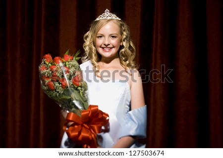 Half length of a beauty pageant winner smiling and holding roses