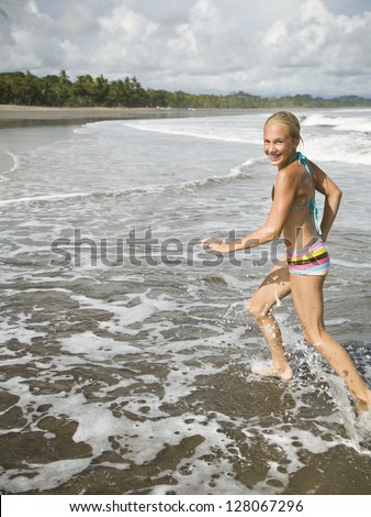 Young girl running in the surf.