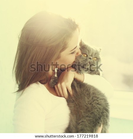 Sunny portrait of a girl who kisses a cat