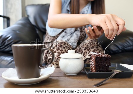 woman eating chocolate cake and coffee in cafe