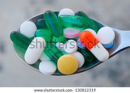 Spoon full with prescription drugs, gel capsules and vitamins