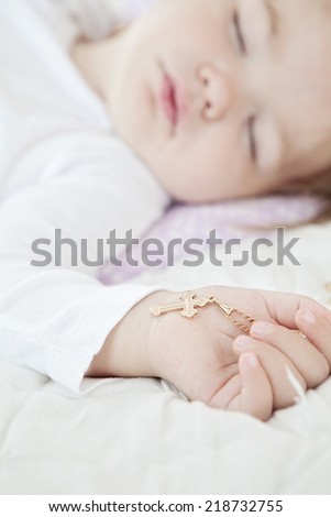baby holding a cross in her hand as symbol of faith