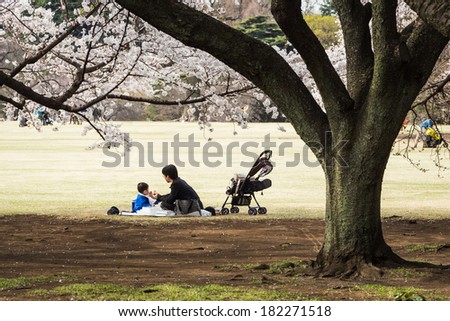 Tokyo, Japan - March 23, 2013: Unidentified child and parent are sitting in Shinjukugyoen park seeing Sakura blossom at Shinjuku, Tokyo, Japan
