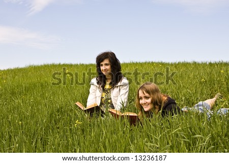 Couple of friends enjoying a book in a meadow