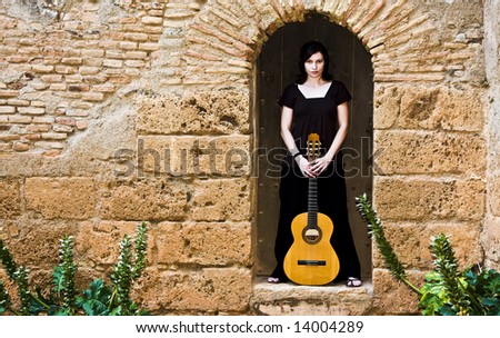 Young guitar performer posing over antique background