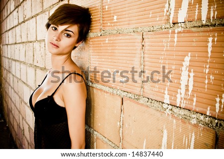 Sexy dressed young woman on dirty brickwall.