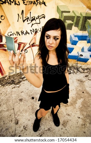 Goth girl looking mirror in urban background.