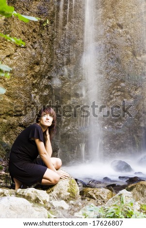 Young woman posing under long exposed waterfall