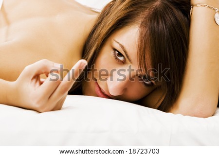 Young woman laying down on the bed doing bad gesture.