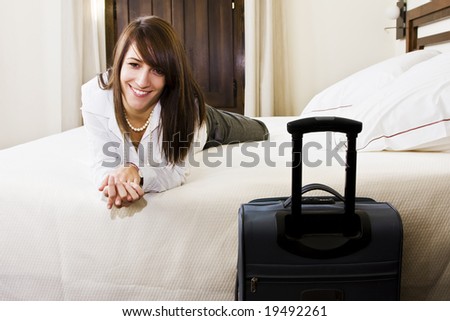 Smiling young businesswoman in bed staring at camera.