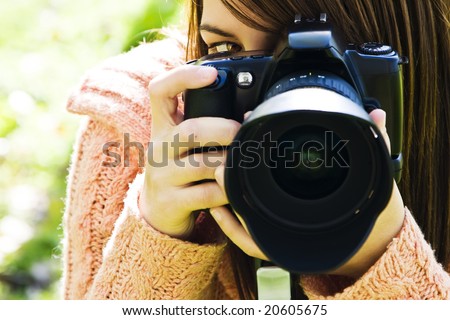 Young woman eye behind slr camera.