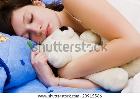 Beautiful sleeping girl with her teddy bear.
