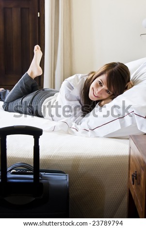 Smiling young businesswoman in bed staring at camera.