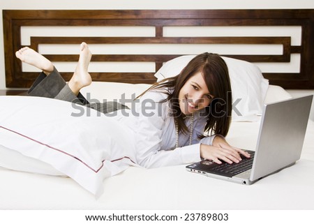 Young smiling businesswoman using laptop in bed