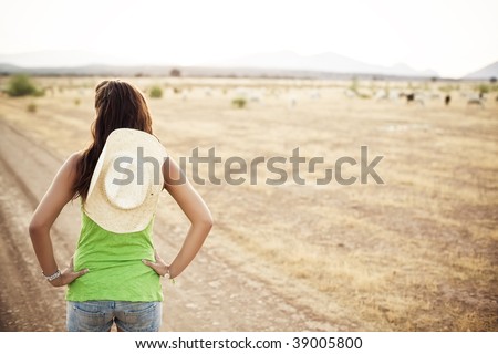 Young unrecognizable cowgirl watching her property
