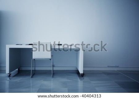 Empty desk facing white wall.
