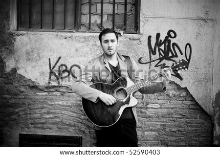 Young attractive street artist playing guitar.