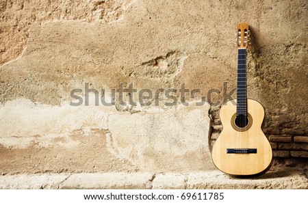 Spanish guitar on old wall, copy spaced.