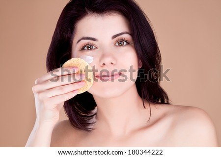 Girl cleans the skin from the face cream sponge