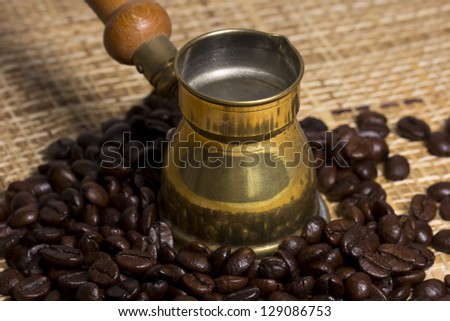 Bronze Turk (Cezve) in the midst of fresh roasted coffee beans light textured surface
