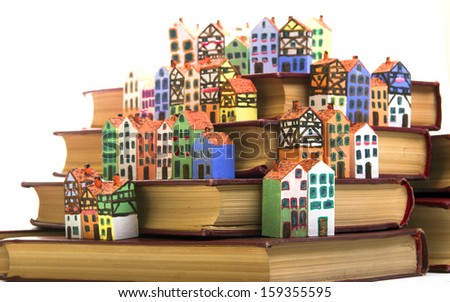 The painted wooden models of typical  buildings of European cities on a small scale with books on a white background. The concept of European culture traditions