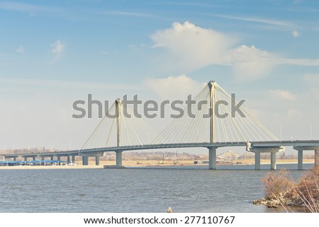 The Clark Bridge under droopy clouds and a pale blue sky seen from the Lincoln-Shields Recreation Area on the Missouri side of the Mississippi River.
