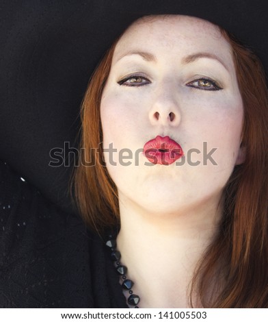 Close-up of a sensual woman in black dress sending a kiss.