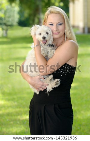 Beautiful young blond woman posing with the her dog in the park