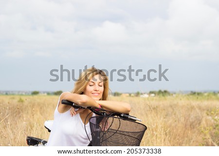Woman relaxing on he bicycle at hay field, portrait, copy space