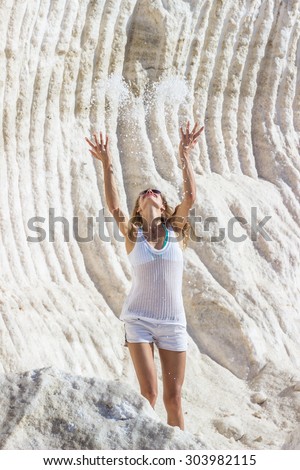 Happy girl throwing up sea salt at salt marsh