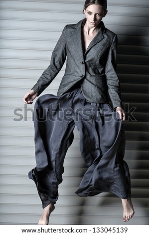 Fashion women jump in suit on gray background without footwear
