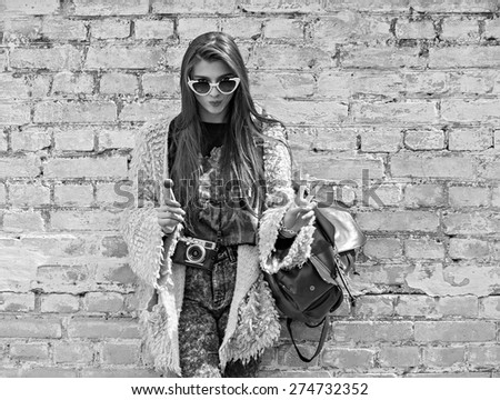 Young fashion girl posing on the background of old brick wall. Outdoors, lifestyle.