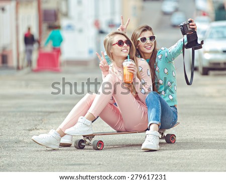 Hipster girlfriends taking a selfie in urban city context, Concept of friendship and fun with new trends and technology.  Best friends eternalizing the moment with modern digital camera