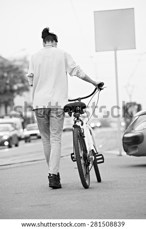 black and white outdoor portrait of young pretty fashion model with bike. Young sexy woman posing in summer.