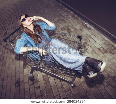 Fun hipster woman glam fashion girl in shopping cart street style