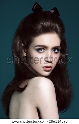 Glamour portrait of beautiful woman model with fresh daily makeup and funny wavy hairstyle. Fashion shiny highlighter on skin, sexy gloss lips make-up and natural eyebrows. gray background