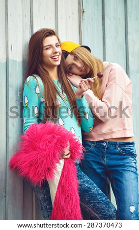 two fashion hipster girlfriends are hugging and having fun in city grunge background