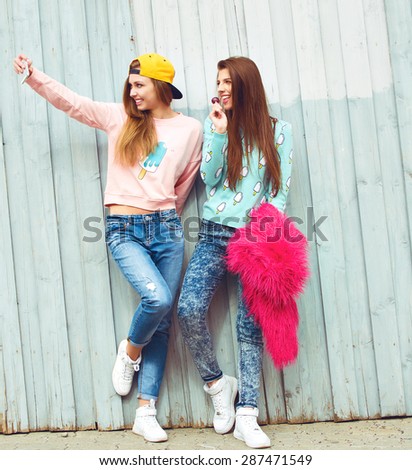 two fashion hipster girlfriends doing photo and having fun in city grunge background