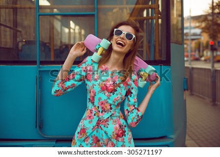 Beautiful and fashion young woman model posing with a skateboard on city street