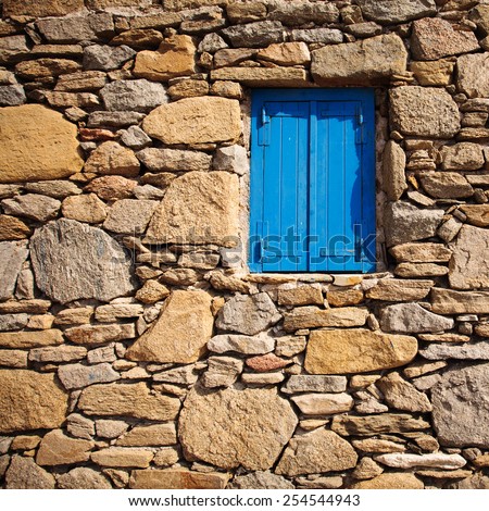 Blue wooden window and rock wall in Mykonos, Greece.