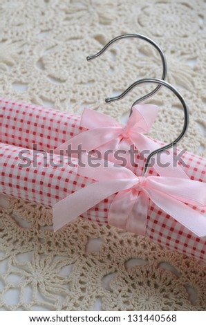 Two tenderly rose clothing hangers with ribbon and bow on crocheted background