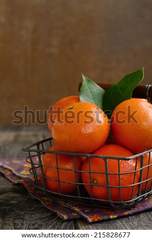 Ripe tangerine fruits in wire basket with copy space on wooden background