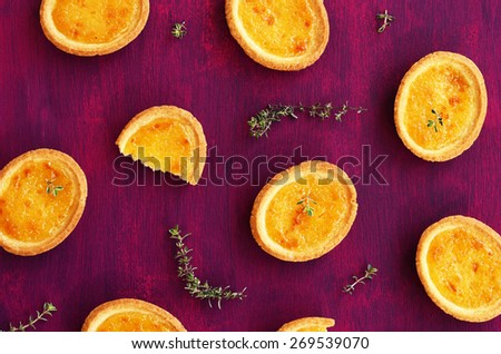 Mini tartlet dessert with lemon filling and thyme on deep lilac background