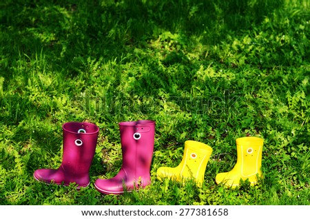 Rubber boots for woman and kid in green summer grass