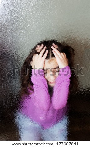 Domestic and family violence. Crying little girl. Look through the glass.