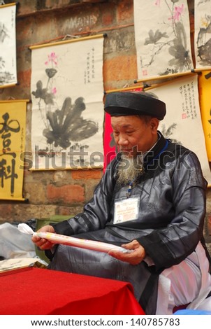 HANOI, VIETNAM, FEBRUARY 14: Old master is writing ancient letter for everyone in lunar new year on February 14, 2013 in Hanoi, Vietnam. This is a tradition of vietnamese people in lunar new year