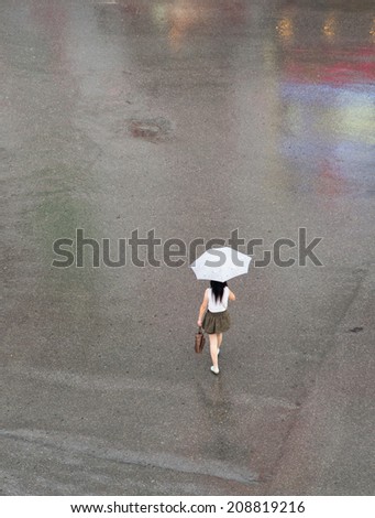 A girl with umbrella on quiet street in raining day in Hanoi, Vietnam
