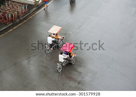 HANOI, VIETNAM, JUNE 28: Cyclos drivers carry tourists in rainy day on June 28, 2014 in Hanoi, Vietnam. Cyclo used to be a popular transportation in Vietnam, it is for tourism now